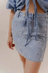 Minifalda de denim celeste con bordado geométrico y aplicaciones de perlas.