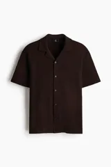 Camisa de manga corta en punto jacquard color marrón, con cuello abierto y cierre frontal de botones.
