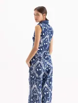 Musculosa azul con estampado de cadenas blancas en piqué de algodón elastizado, escote en V con cuello polo y sin mangas.