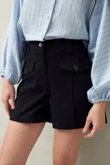 Short de tiro alto color beige, con bolsillos delanteros con solapa y botones a la vista.