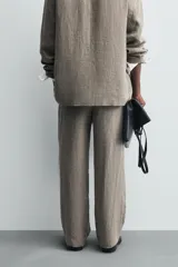 Pantalón de corte straight relaxed fit confeccionado en tejido de lino con efecto lavado. Presenta cierre frontal con cremallera y botón, bolsillos laterales y bolsillos traseros de vivo.