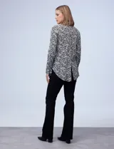 Camisa estampada blanca y negra con cuello clásico, abertura frontal con botones ocultos y mangas largas con puños abotonados.