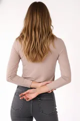 Remera blanca de manga larga, entallada, con cuello redondo y una hilera de botones en el frente. Incluye un pequeño bolsillo decorativo en el pecho.