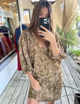 Vestido corto de color verde militar con estampado floral, escote en V con ribete contrastante, mangas tres cuartos abullonadas con puños elastizados y diseño holgado.