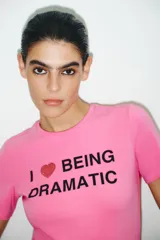 Camiseta rosa de cuello redondo y manga corta con estampado frontal de la frase "I ❤️ BEING DRAMATIC" con strass. Corte slim fit.
