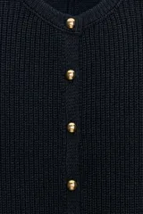 Chaqueta de punto color azul marino, con cuello redondo, mangas por debajo del codo y bajo en evasé. Cuenta con cierre frontal de botones dorados.