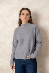 Buzo de punto color visón con cuello alto, manga larga y diseño holgado. Presenta un bordado floral en relieve al tono en la parte frontal.