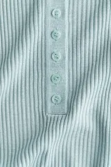 Remera de manga larga en punto acanalado, de diseño entallado, con cuello redondo y tapeta frontal con botones del mismo tono.