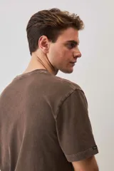 Remera de calce relajado y cuello redondo, color verde musgo con efecto lavado, y pequeño bordado de un morrón en el pecho.