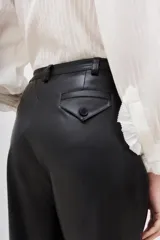 Pantalón estilo capri de efecto cuero negro, con corte holgado y detalles de costuras geométricas en la parte delantera.