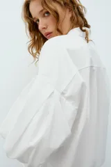 Camisa roja de cuello solapa, con mangas cortas abullonadas tipo globo y cierre frontal con botones ocultos.