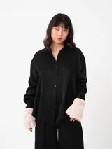 Camisa negra de corte amplio con textura arrugada, cuello clásico y mangas largas con puños.