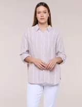 Camisa de lino de la marca Dash, color beige con rayas verticales blancas. Cuenta con cuello camisero, cierre frontal con botones, un bolsillo aplicado en el pecho y mangas largas con sistema de ajuste para arremangar.