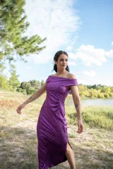 Vestido midi color violeta con textura brillante, escote off-shoulder y mangas cortas.