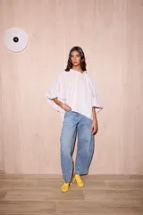 Camisa holgada de algodón con cuello alto y mangas anchas, confeccionada en Italia. Presenta un estampado de rayas verticales finas en tonos beige, blanco, amarillo, rojo y azul.