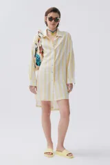 Camisa celeste y blanca a rayas verticales, de calce holgado y hombro caído, con botones al frente.