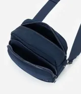 Cartera bandolera de tamaño pequeño, confeccionada en poliéster con estructura ligeramente acolchada. Cuenta con un bolsillo delantero con cierre, compartimento principal con cierre doble y correa ajustable.