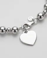 Pulsera de esferas metálicas de plata con dije colgante en forma de corazón.