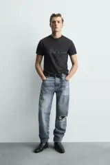 Remera negra de corte cropped, con cuello redondo y manga corta. Presenta estampado frontal con texto en efecto desgastado.