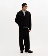 Campera tipo trucker de gamuza sintética color negro, con cuello clásico, bolsillos delanteros con solapa y cierre frontal por botones metálicos.
