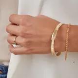 Esclava rígida de oro 18k con acabado satinado y diseño de cinta plana. Presenta una textura fina en su superficie y un diseño minimalista.