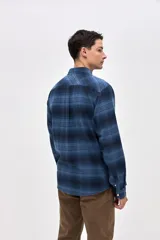 Sobrecamisa de algodón con diseño a cuadros en tonos azules, cuello clásico, cierre frontal con botones y dos bolsillos en el pecho con solapa.