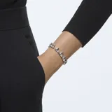 Pulsera rígida plateada con cristales transparentes de talla triangular engarzados en hilera.