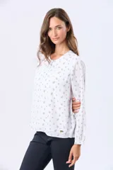 Blusa de manga larga con cuello redondo y cierre frontal de botones. Presenta un estampado floral en color negro sobre fondo blanco.