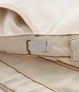 Pantalón femenino curve & plus size color beige, confeccionado en sarga de algodón certificado. Presenta un modelo recto, cierre delantero con botón y cremallera, bolsillos delanteros y traseros funcionales, y bajo con acabado deshilachado.