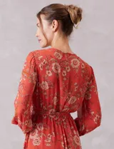 Vestido midi de gasa estampada con diseño floral, escote en V cruzado, cintura elastizada con lazo de ajuste y mangas largas con puños fruncidos. Incluye forro interno a tono.