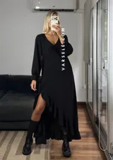 Vestido largo color marrón, con escote en V, mangas largas con puños y detalle de encaje en el pecho. Presenta un diseño asimétrico con volados en el ruedo y una abertura frontal.