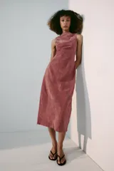Vestido midi de piel color rosado, con cuello redondo y diseño sin mangas. Presenta costuras marcadas y cierre en la espalda con cremallera oculta.