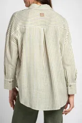 Camisa de corte oversize con estampado de rayas verticales, cuello clásico, cierre frontal con botones y bolsillo en el pecho. Presenta mangas largas con puños abotonados y un diseño fluido.