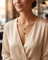 Collar doble de acero con baño de oro, con diseño reversible en nácar y ónix, compuesto por dos cadenas con dijes circulares y detalles de esferas.