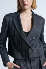 Blazer cropped de sarga con diseño a rayas verticales, corte entallado y cierre frontal cruzado con botones. Presenta detalles desflecados en los hombros y en el canesú trasero, además de flecos de seda desmontables en la solapa.