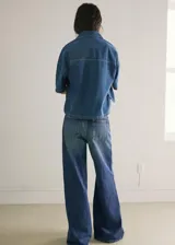 Jeans de denim azul de tiro medio y diseño wide leg largo, con cinco bolsillos, trabillas para cinto y cierre de botón y cremallera.
