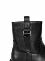 Bota corta de cuero sintético color negro, con suela track dentada y detalle de hebilla metálica en el lateral superior.