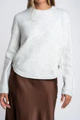 Sweater de punto gris melange, de manga larga y cuello redondo. Presenta un detalle de botones marrones en el lateral.