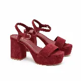 Sandalia de fiesta Dalia color bordó, confeccionada en gamuza de cuero legítimo. Cuenta con diseño de tira frontal ancha, taco ancho, plataforma y pulsera ajustable al tobillo con hebilla metálica.