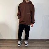 Canguro negro oversize con capucha y bolsillo tipo canguro. Presenta una estampa pequeña con la frase "feel the vibes" en el pecho y un logo en la parte inferior.