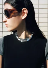 Top negro de algodón con cuello redondo y mangas cortas, con fucsia y detalle de lazo integrado para atar en la cintura.