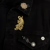 Set de dos pins: uno con forma de rosa en color crema con contorno negro y otro con forma de tigre dorado.