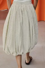 Falda midi de tiro medio color beige con estampado de cuadros finos oscuros. Presenta pliegues en la cintura y bajo abullonado con acabado evasé, de Zara Woman Collection.