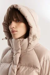 Campera puffer corta color beige con capucha desmontable, cierre frontal con cremallera y botones a presión, y cordón ajustable en el ruedo. Diseño acolchado con bolsillos laterales.