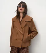 Campera pesada de estructura firme, color marrón, con cuello amplio de solapa alargada, cierre cruzado con botones, mangas largas y bolsillos delanteros. Presenta un canesú sobrepuesto en la espalda con pliegue central.