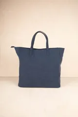 Bolso tipo tote color marrón con tachas plateadas en los bordes y monedero colgante con cierre.