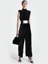 Mono largo de terciopelo negro con cuello alto, sin mangas, corte holgado y cinturón ancho plateado.