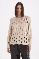 Sweater de punto color beige con diseño de calados circulares en toda la prenda, cuello redondo y mangas largas con puños acanalados.