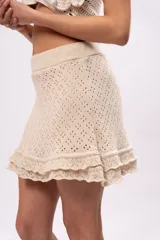 Minifalda color crema de tejido crochet con cintura elástica y volados en el ruedo.