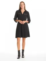 Vestido de crepe color marrón, con cuello solapa, escote en V y cintura elastizada. Presenta bolsillos simulados con cierres metálicos en el frente y mangas largas regulables con presilla y botón.